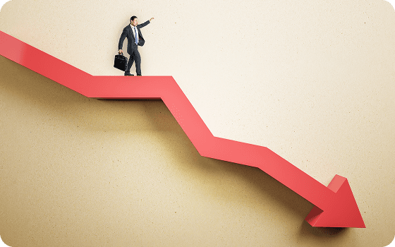 A businessman standing on a red declining arrow chart